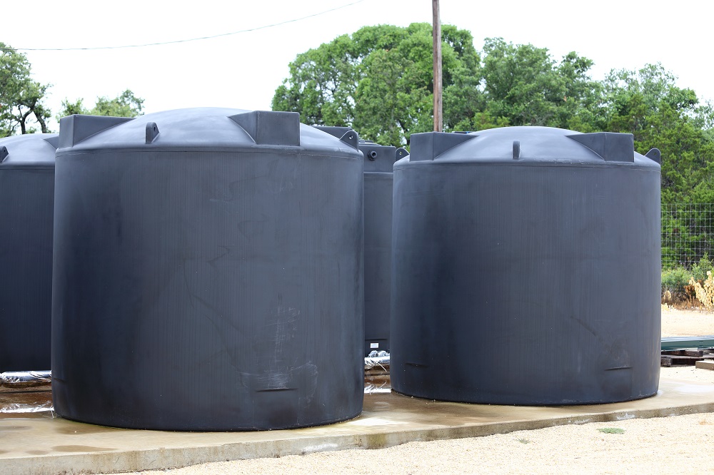 Water tanks holding rain water sit on a concrete slab.